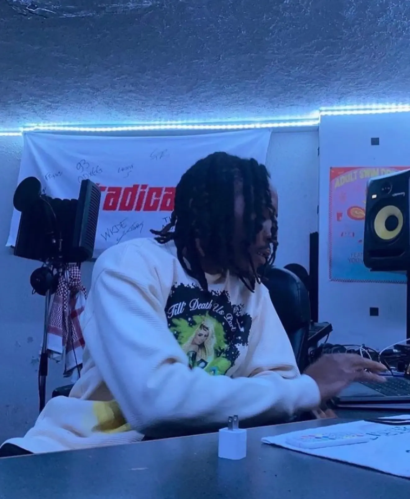 Light-colored graphic sweatshirt shown being worn in a music workspace