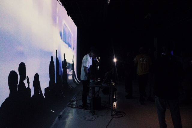 Silhouettes of people in front of a large projection during a live event.